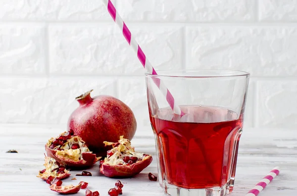 Granatäpplejuice i glas och granatäpplen på vit trä bac — Stockfoto