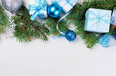 mavi ve beyaz hediye kutuları bir kurdele ile çam dalları bağlı,