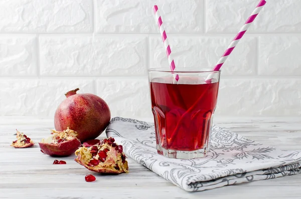 Granatäpplejuice i glas och granatäpplen på vit trä bac — Stockfoto