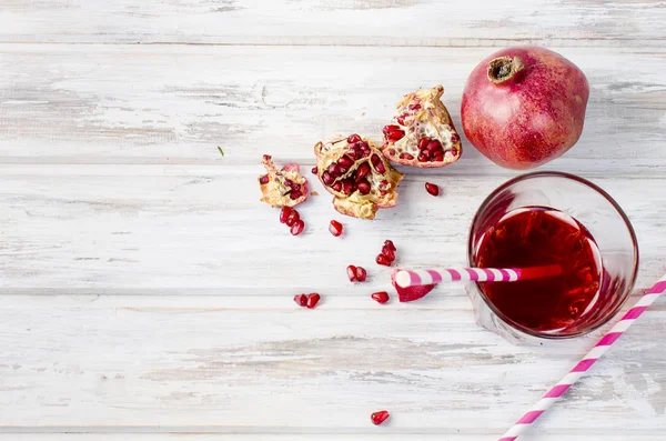 Granatäpplejuice i glas och granatäpplen på vit trä bac — Stockfoto