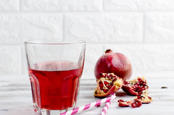 Granatäpplejuice i glas och granatäpplen på vit trä bac — Stockfoto