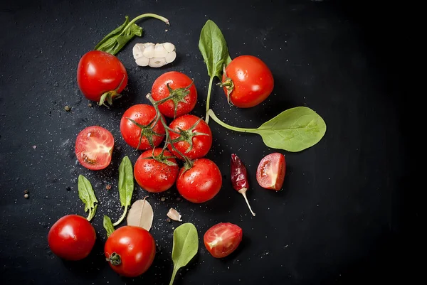 Negro mesa rústica con rama de tomates y hierbas, top vie —  Fotos de Stock