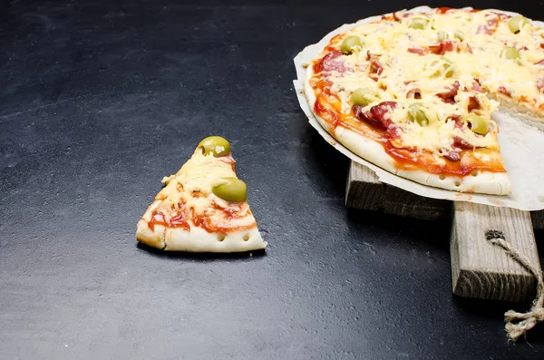 Leckere Pizza mit Gewürzen und Oliven auf schwarzem Hintergrund — Stockfoto