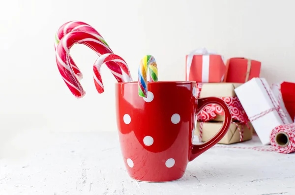 Red cup of lollipops and gifts on the white background — Stock Photo, Image