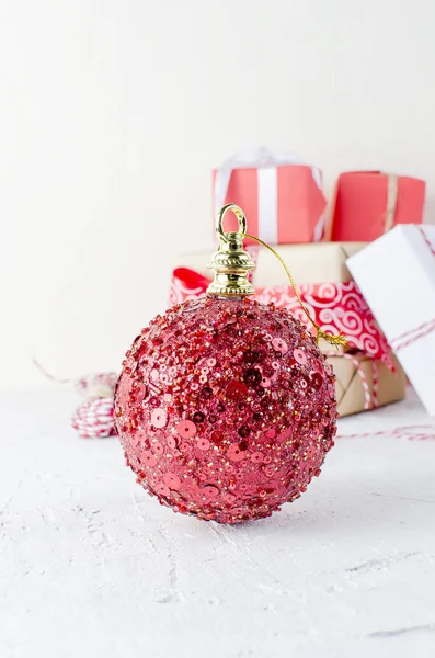 Bola de Natal grande vermelho e caixas de presente amarradas com uma fita vermelha — Fotografia de Stock