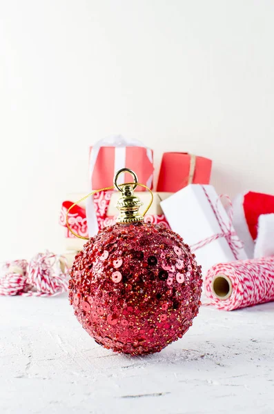 Κόκκινη μεγάλη Χριστουγεννιάτικη μπάλα και κουτιά δώρου δεμένα με μια κόκκινη κορδέλα — Φωτογραφία Αρχείου