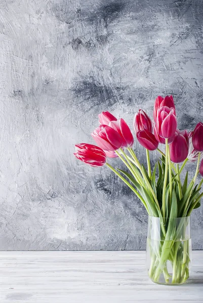 Bouquet of pink tulips in a glass vase  on grey background. — Stock Photo, Image