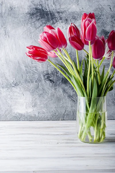 Bouquet of pink tulips in a glass vase  on grey background. — Stock Photo, Image