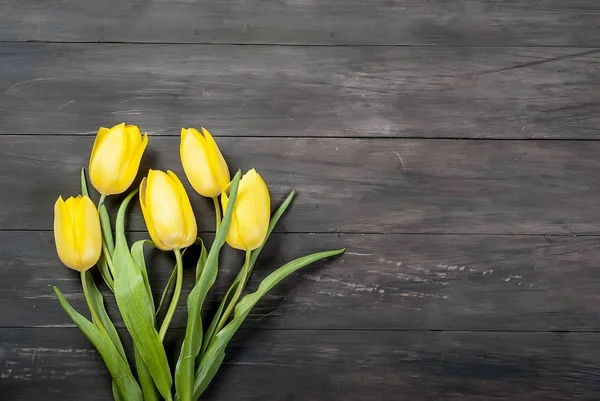 Buquê de tulipas amarelas com uma fita amarela em um backgr de madeira — Fotografia de Stock