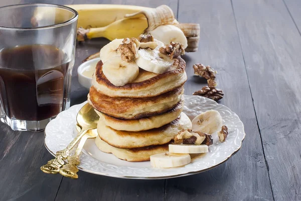 Panqueques con plátano, nueces, miel y café taza sobre fondo oscuro — Foto de Stock