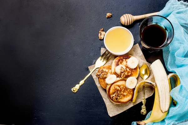 Panquecas com banana, nozes, mel e xícara de café no backgro escuro — Fotografia de Stock