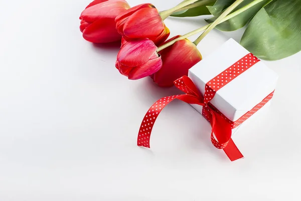 Bukett Röda tulpaner, påskliljor och gåva på den vita bak — Stockfoto