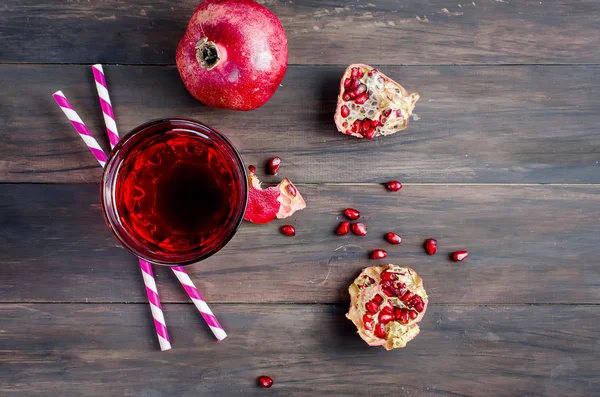 Granatäpplejuice i glas och granatäpplen på mörka trä bac — Stockfoto