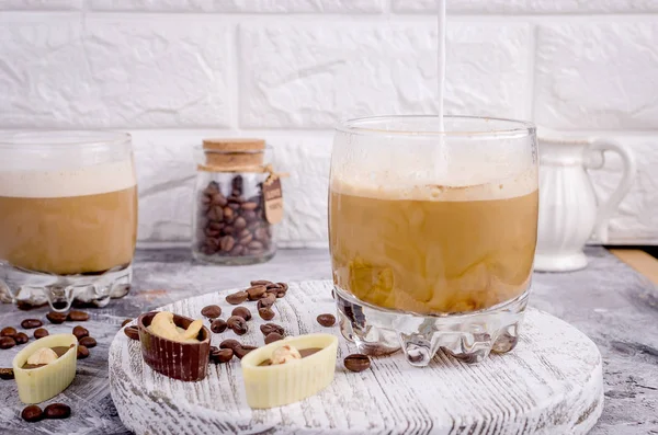 Verser du lait dans un verre avec du café — Photo