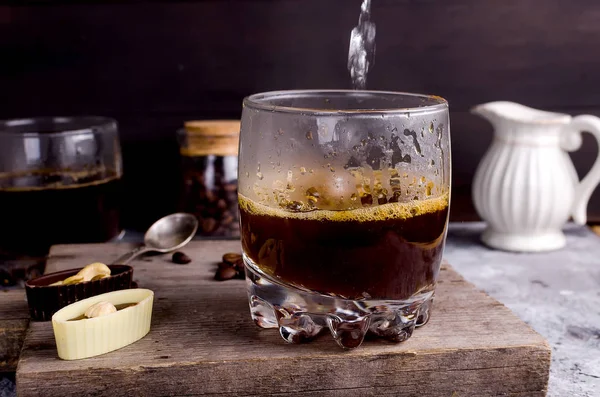 Pouring boiling water into a glass of coffee — Stock Photo, Image