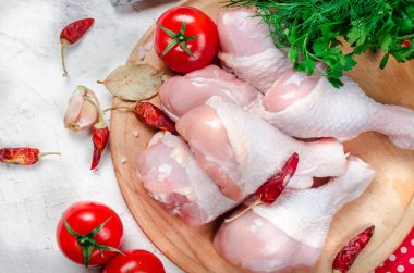 Baharat ve otlar ile kesme tahtası üzerinde çiğ tavuk budu.