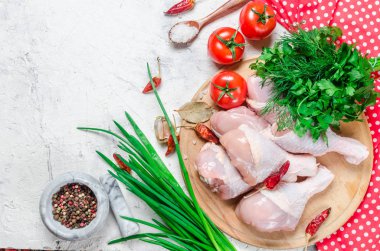 Baharat ve otlar ile kesme tahtası üzerinde çiğ tavuk budu.