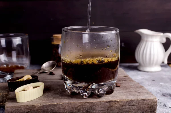 Pouring boiling water into a glass of coffee — Stock Photo, Image