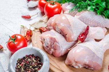 Baharat ve otlar ile kesme tahtası üzerinde çiğ tavuk budu.