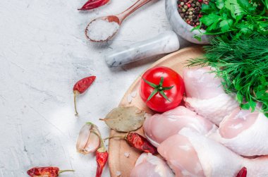 Baharat ve otlar ile kesme tahtası üzerinde çiğ tavuk budu.