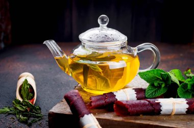 Çaydanlıkta naneli sıcak çay ve kuru meyveli deri rulo.