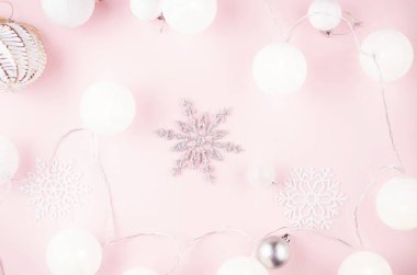 Beyaz toplar, dekoratif kar taneleri ve pembe bir Noel çelengi.