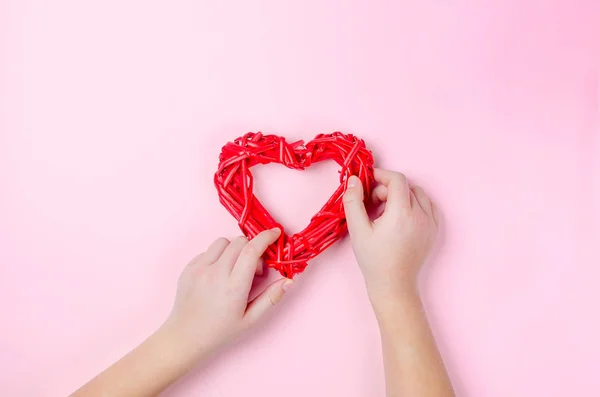 Wicker heart of twigs in the hands of a girl on pink — Stockfoto