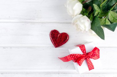 Gift box with bouquet of white rose on white wooden background.