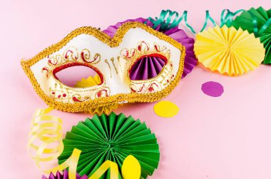 Renkli kağıt konfetileri, karnaval maskesi ve fotokopi alanı, tebrik kartı ve doğum günü için parti davetiyesi tasarımı olan pembe arka planda renkli bir yılan balığı, Mardi Gras,