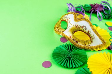 Renkli kağıt konfetileri, karnaval maskesi ve fotokopi alanı, tebrik kartı ve karnaval veya doğum günü için parti davetiyesi tasarımı olan yeşil arka planda renkli bir yılan.,