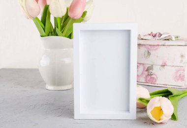 Seramik sürahide boş beyaz çerçeveli pastel lale buketi. Bahar ya da tatil konsepti, Paskalya ya ya da Sevgililer Günü, doğum günü. Boşluğu kopyala, şablon düzenleme tebrik kartı, metin için yer, 