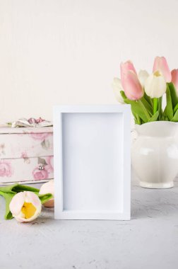 Seramik sürahide boş beyaz çerçeveli pastel lale buketi. Bahar ya da tatil konsepti, Paskalya ya ya da Sevgililer Günü, doğum günü. Boşluğu kopyala, şablon düzenleme tebrik kartı, metin için yer, 