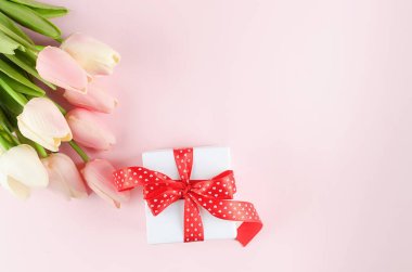 Pastel pembe arka planda pembe ve beyaz lalelerle dolu bir hediye kutusu. Bahar ya da tatil konsepti, 8 Mart, Uluslararası Kadınlar Günü, doğum günü. Boşluğu, düzlüğü, metin için yeri olan şablon düzenleme tebrik kartını kopyala, 