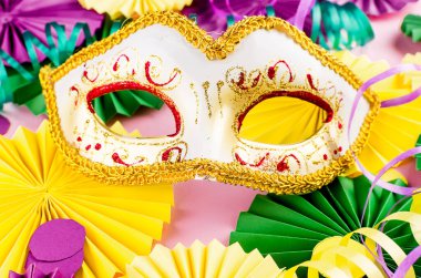 Renkli kağıt konfetileri, karnaval maskesi ve fotokopi alanı, tebrik kartı ve doğum günü için parti davetiyesi tasarımı olan pembe arka planda renkli bir yılan balığı, Mardi Gras,