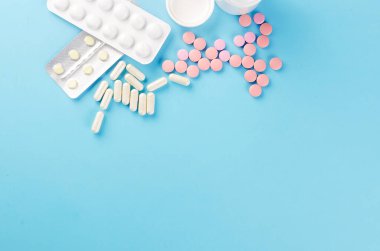 İlaç konsepti, çeşitli haplar, şırınga, mavi arka planda tıbbi eldivenler, fotokopi alanı modeli, düz yatak.