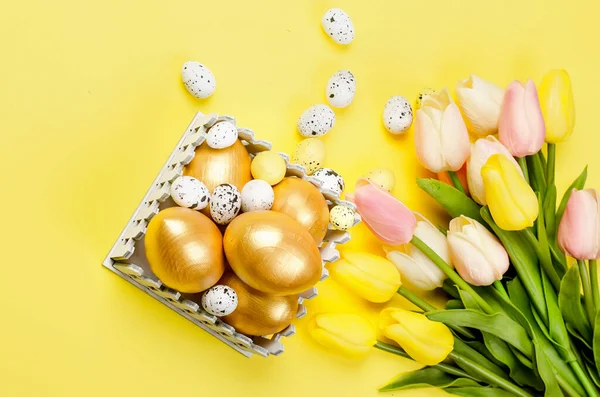 Easter dekorations. decorative easter golden eggs, pussy-willow twigs  and tulips on a yellow background, Spring holiday concept. Copy space, Easter card layout template with place for text, mockup, flat lay,
