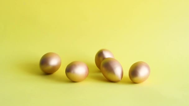 Ovos Decorativos Ouro Rolando Bater Uns Aos Outros Fundo Amarelo — Vídeo de Stock