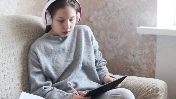 Adolescente Com Fones Ouvido Livro Didático Tablet Sentado Sofá Casa — Vídeo de Stock