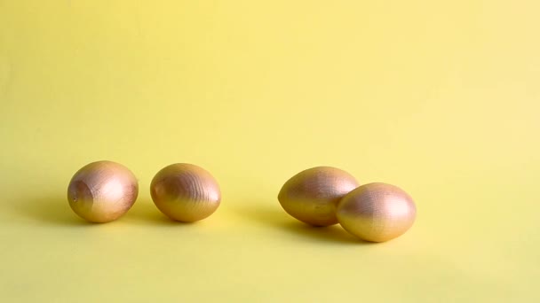 金の装飾卵が転がって黄色の背景をノックする 春休みのコンセプト コピースペース テンプレートモックアップイースターグリーティングカード — ストック動画