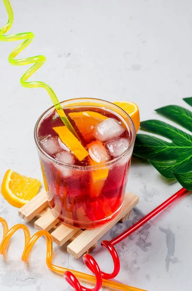 Summer homemade Cold red sangria cocktail with Orange and ice in glass on gray concrete stone background