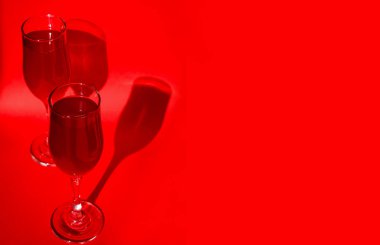 Kırmızı arka planda kırmızı köpüklü kırmızı şarap ve gölgeli iki bardak kokteyl. Minimalist yaratıcı sanat kompozisyonu. Kavramsal görüntü. Basit görsel kavram.