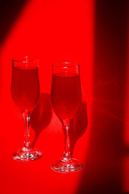 Kırmızı arka planda kırmızı köpüklü kırmızı şarap ve gölgeli iki bardak kokteyl. Minimalist yaratıcı sanat kompozisyonu. Kavramsal görüntü. Basit görsel kavram.