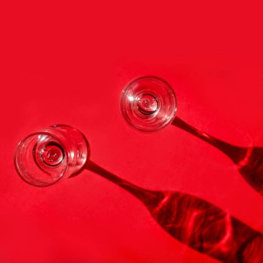 Kırmızı arka planda gölgeli iki boş bardak. Minimalist yaratıcı sanat kompozisyonu. Kavramsal görüntü. Basit görsel kavram.