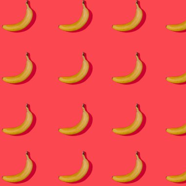 Kusursuz desenli, kırmızı arka planda gölgesi olan olgun sarı muzlu. tatil konsepti. Şenlik arka planı. Düz yatıyordu. Yaratıcı kompozisyon, pop-art tarzında soyut renkli meyve arkaplanı.