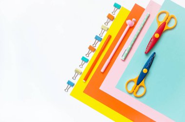 Sıraya dizilmiş renkli kağıtlar, pastel boyalar, makas ve malzemeler beyaz bir masada. Çocuk sanatı, çocuklar için zanaat ya da bir çocuğu okula hazırlamak. Yaratıcılık Masaüstü 