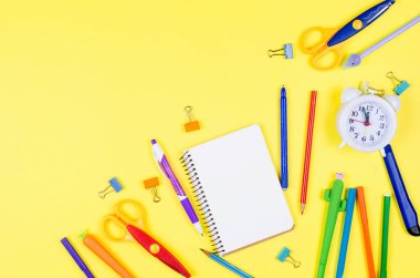 Sarı kağıtta farklı renkte okul malzemeleri var. Defter, kalem, kalem ve diğer aletler. Okul geçmişine dönelim. Düz konum, üst görünüm, kopyalama alanı. Site için pankart.