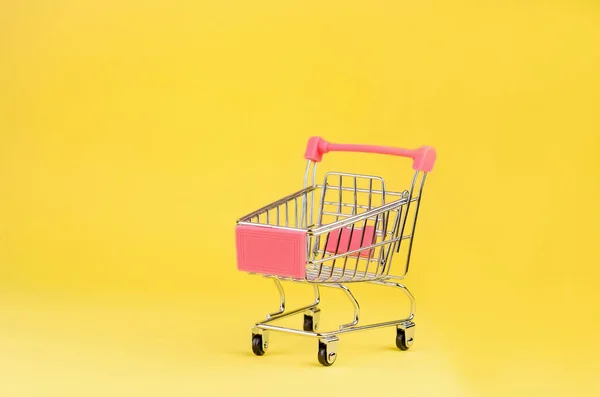 超级市场的小购物车推着装有黄色背景轮子的购物车 购物者 销售或购买 消费者概念 — 图库照片