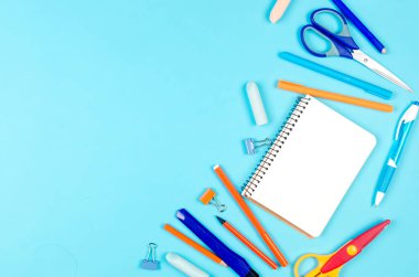 Not defteri, mavi arka planda mavi ve turuncu okul malzemeleri. Eğitim konsepti. Kopyalama alanı ile yukarıdan görüntüle. Model, düz yatak.