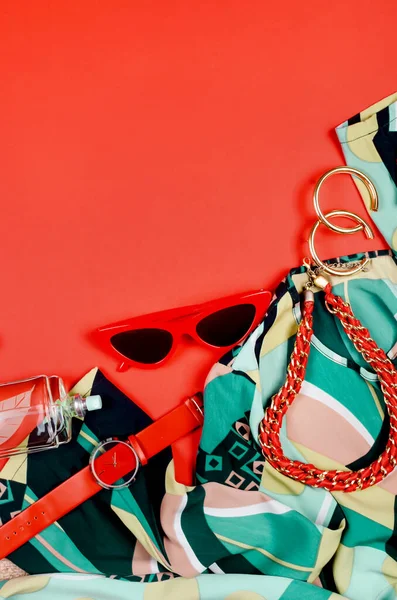Women's Summer red and green outfit set of clothes and accessories - dress, shoes, sun glasses, watches and perfume background. Flat lay female casual style look. Top view. Copy space.