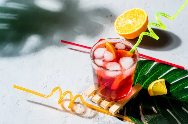 Summer homemade Cold red sangria cocktail with Orange and ice in glass on gray concrete stone background